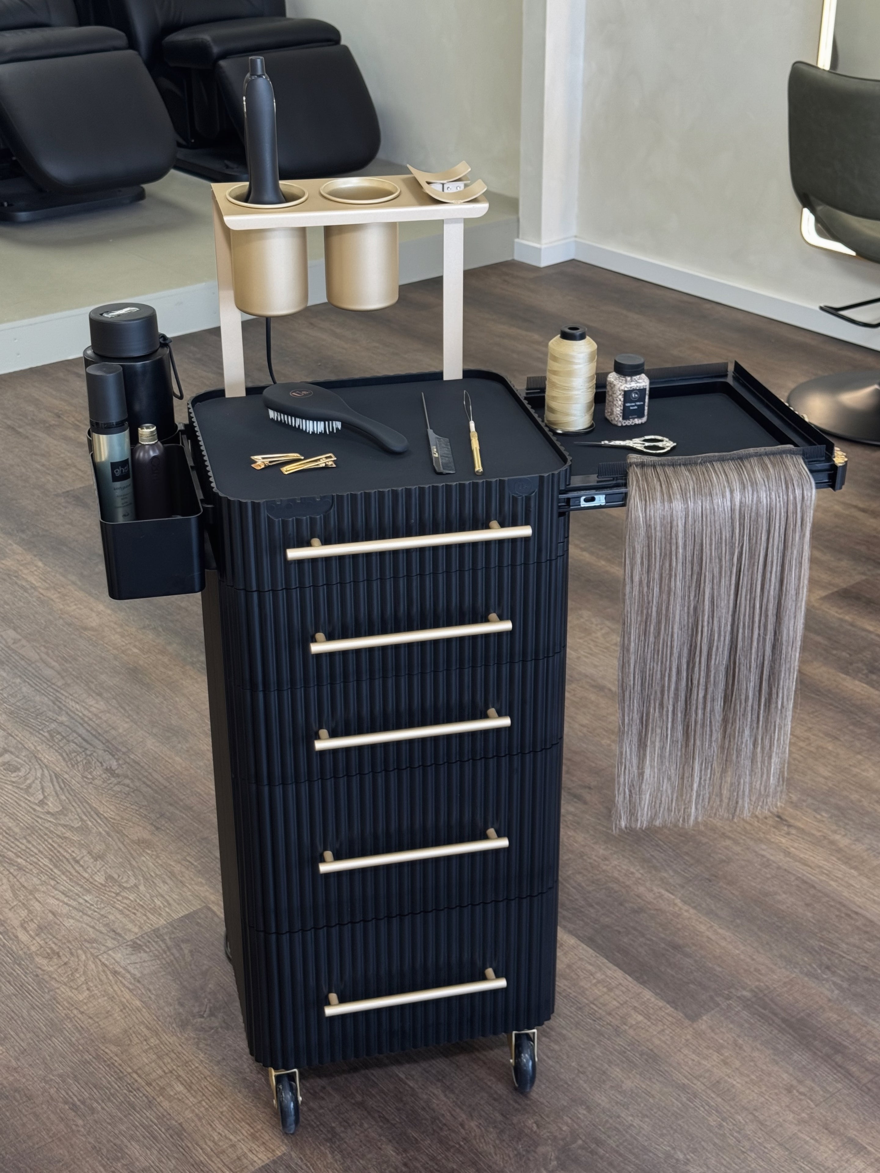 Black hair styling cart with tools and supplies in a salon setting