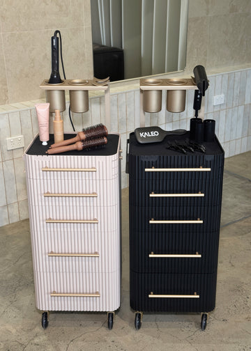 Two salon carts, one white and one black, with hair tools on a tiled floor.