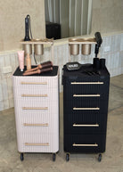 Two salon carts, one white and one black, with hair tools on a tiled floor.