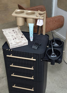 Black hair styling station with tools and products on a gray floor.